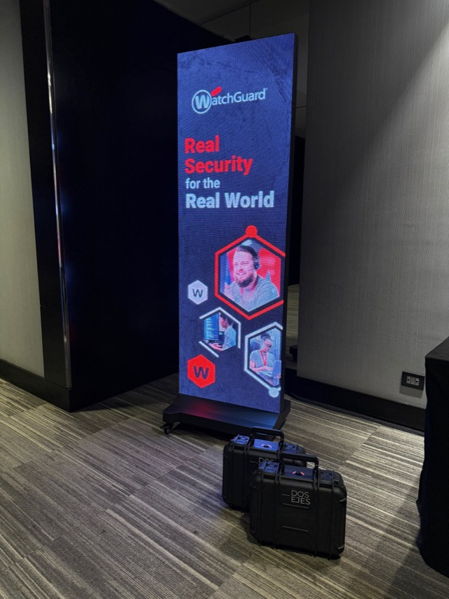 Pendón LED indoor de Dos Ejes montado en un evento corporativo de WatchGuard, con las cajas de transporte de Dos Ejes en primer plano